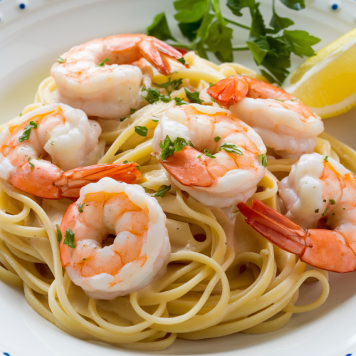 Finished shrimp scampi pasta plated with fresh parsley garnish and lemon wedge