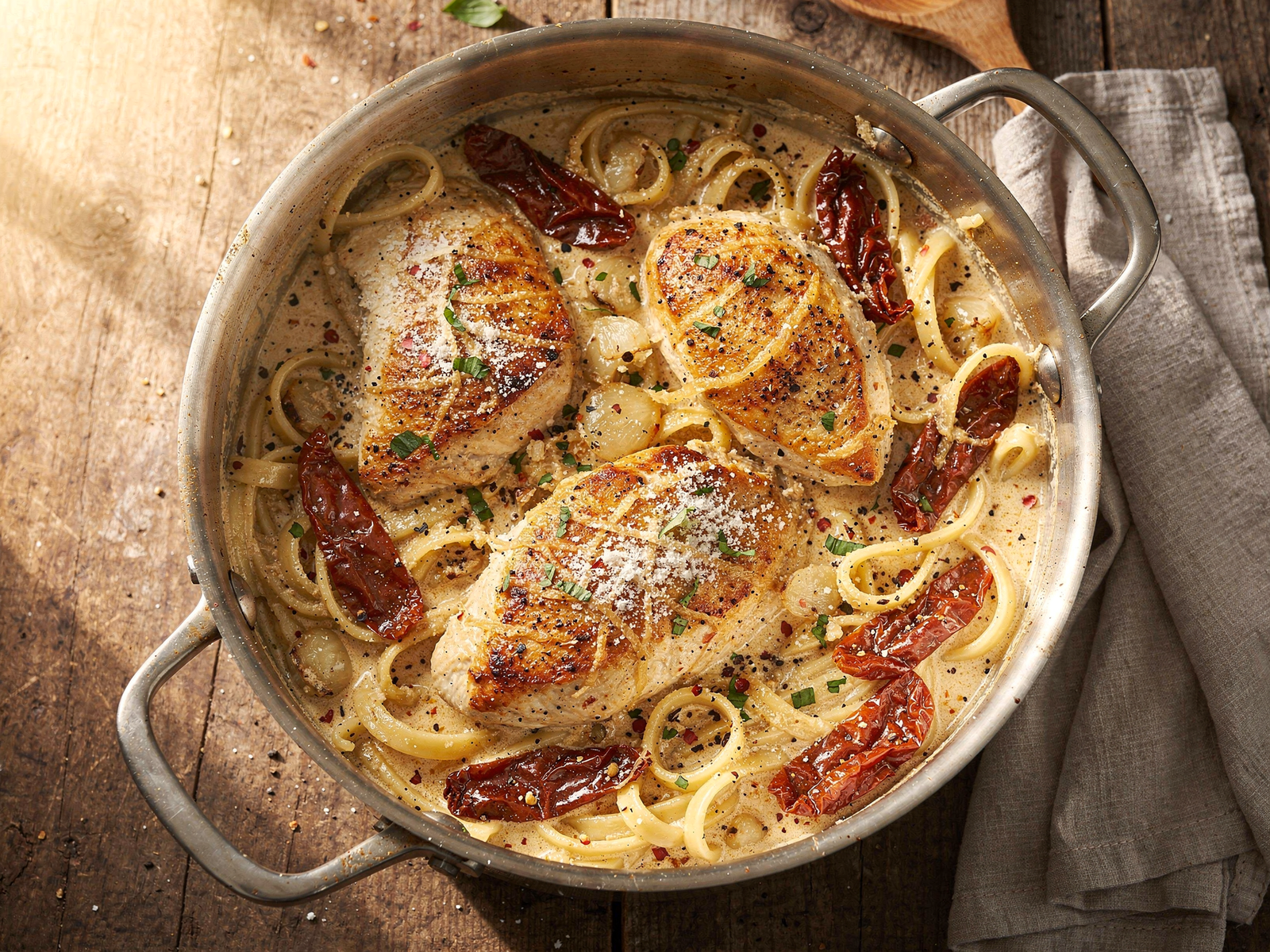 A large pot showing golden browned chicken breasts and sautéed garlic with sun-dried tomatoes in a Marry Me chicken pasta one pot recipe