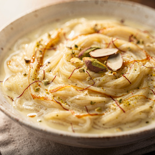 A close-up of creamy Easy Vermicelli & Fine-Pasta Milk Desserts showing the rich texture with visible saffron strands and cardamom flavor in a ceramic bowl